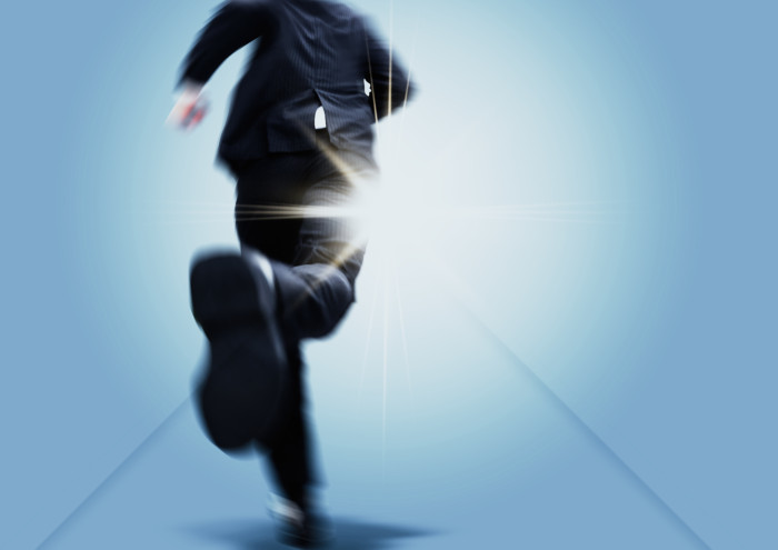 光の射す方向を目指して走るビジネスマン